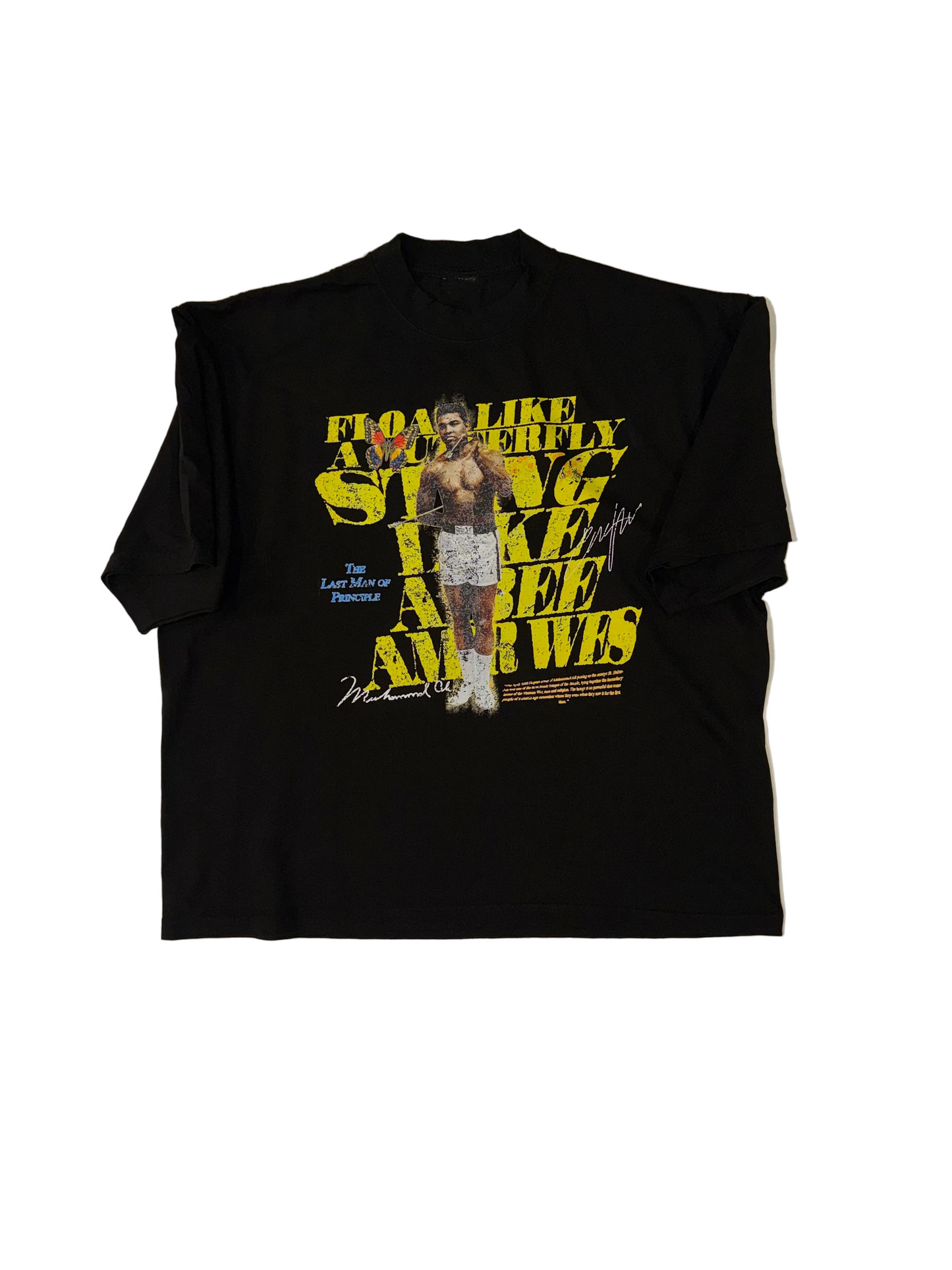 A black short-sleeve graphic t-shirt laid flat on a white background. The shirt features a large front print with yellow text reading 'FLOAT LIKE A BUTTERFLY STING LIKE A BEE LIKE A BEE' and a central image of Amir Wes.